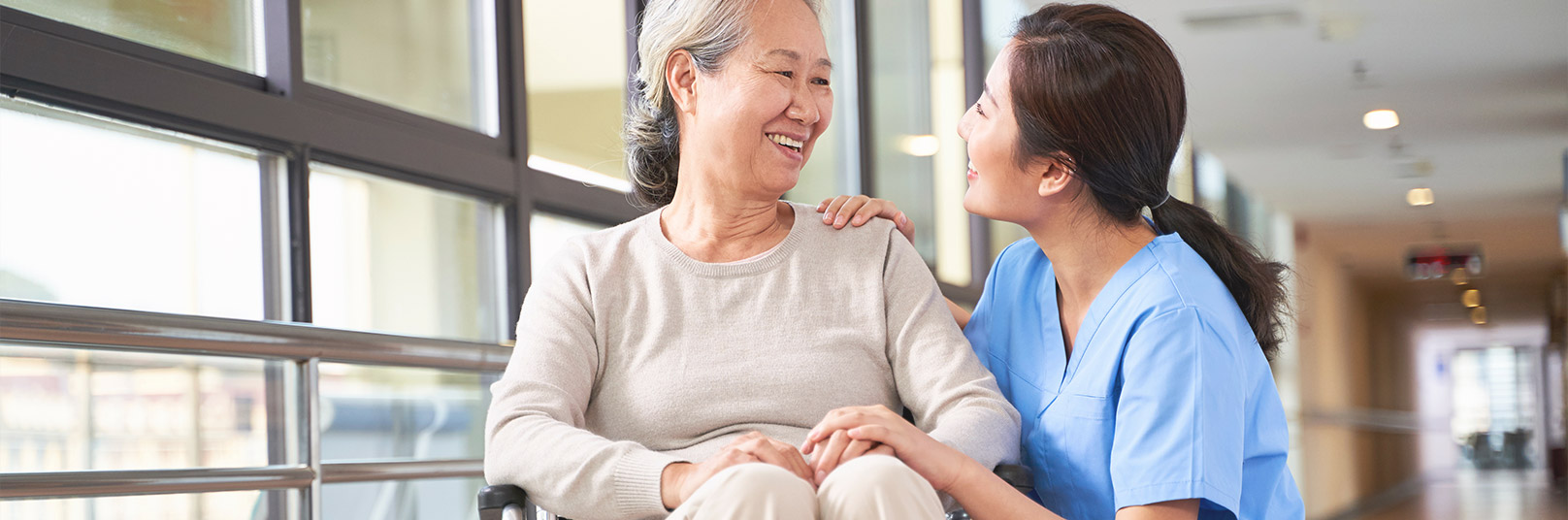 A female nurse is looking at a patient sitting on a wheel chair