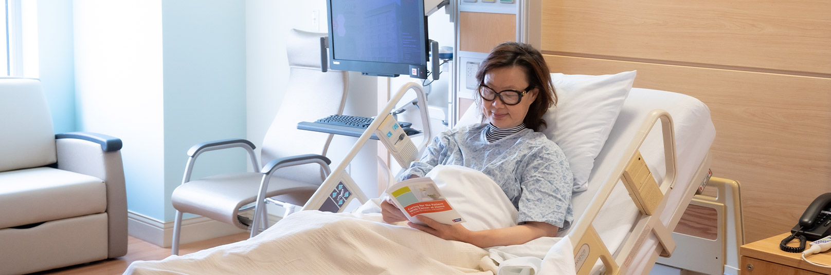 Smiling patient reading in her hospital bed