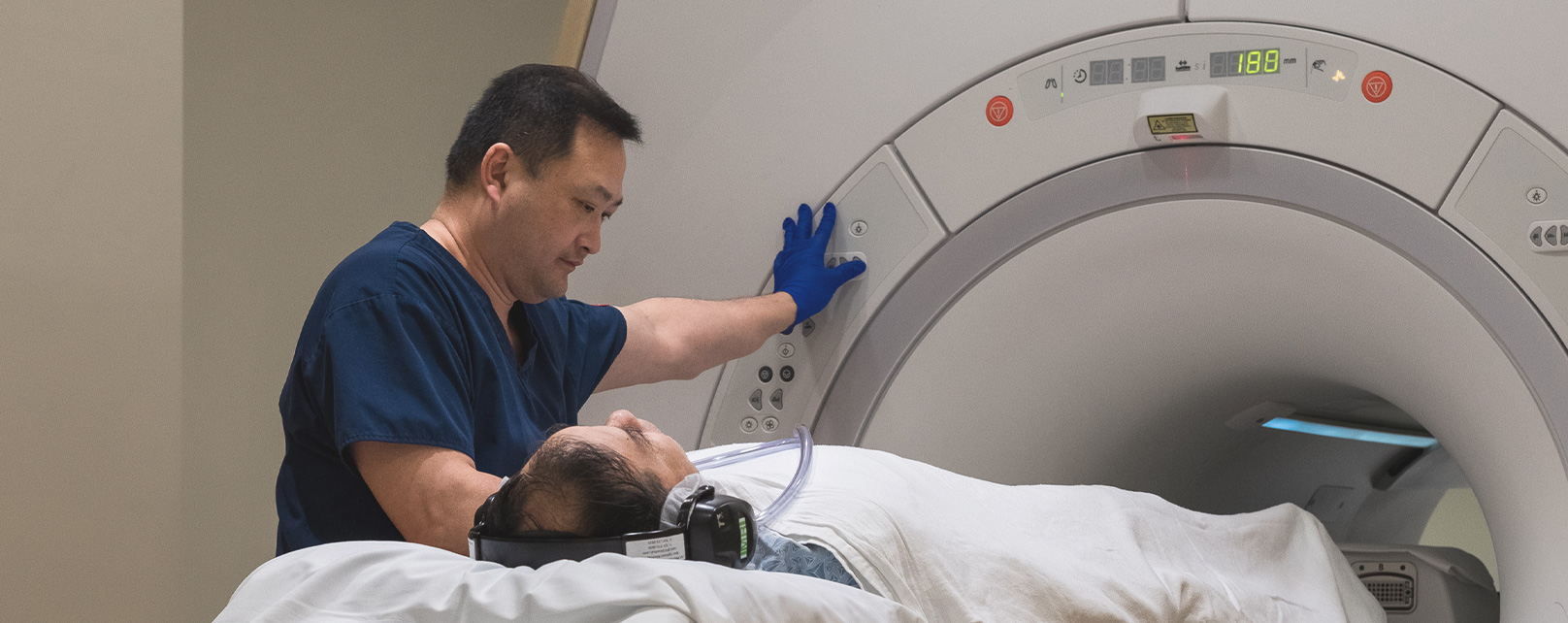 Radiology technician operating MRI machine and sending patient into the machine
