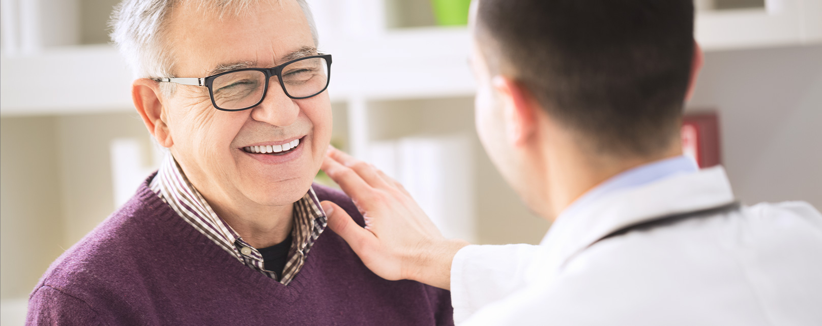 a doctor put his hand on a smiling elderly male patient's shoulder