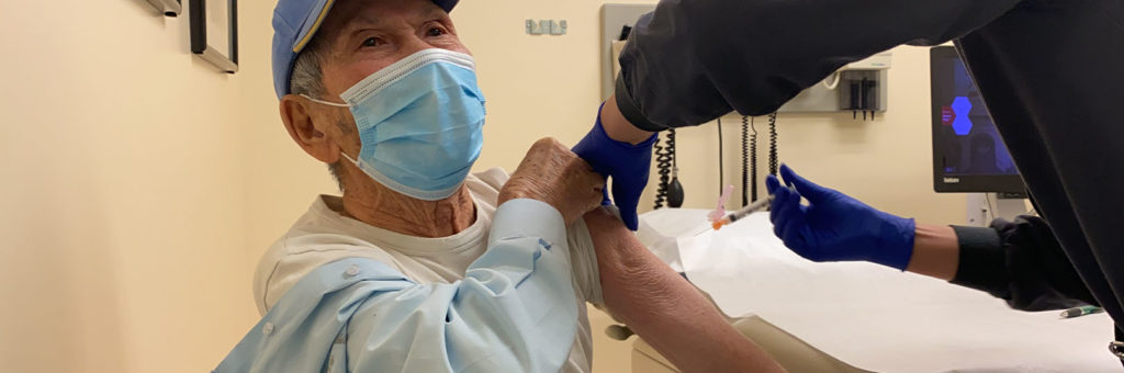 Baseball cap-wearing man getting vaccination at Chinese Hospital Clinic