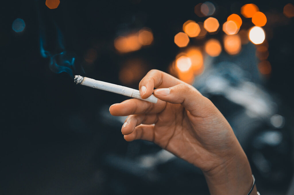 A lit cigarette held between someone's fingers.