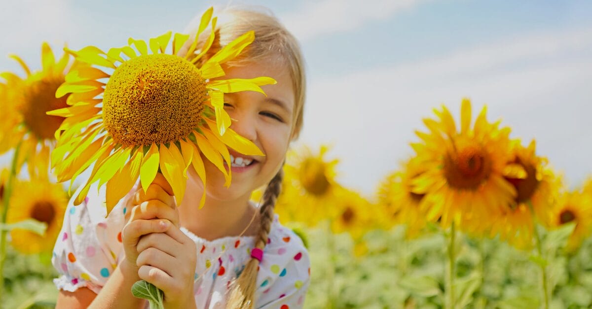 a girl holding a sunflower in a sunflower field