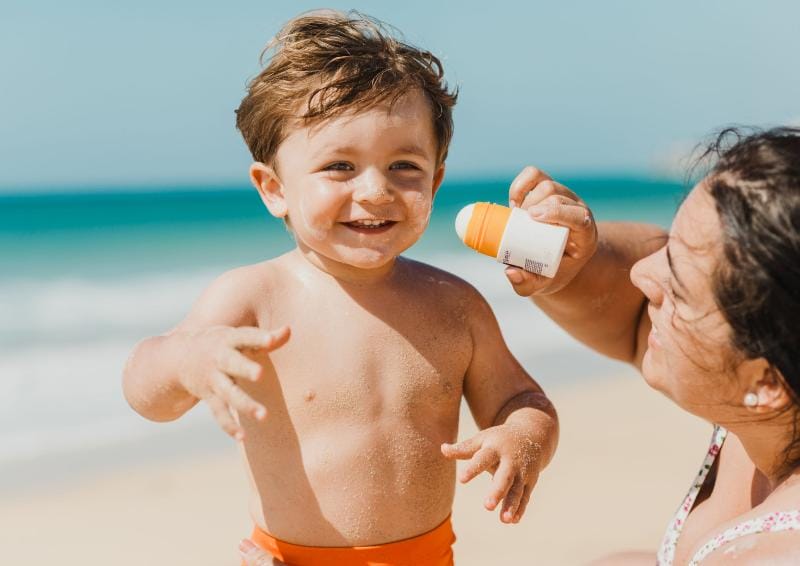 a woman applying sunscreen on a child's face