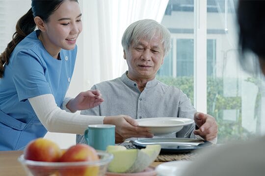 Caregiver serving meal to elderly