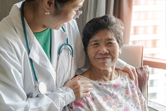 Doctor comforting elderly patient indoors.